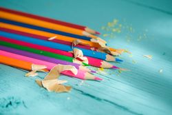 Coloured pencils arranged in a circle on a wooden background