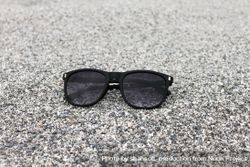 Sunglasses sitting on grey sand 0gZZeb
