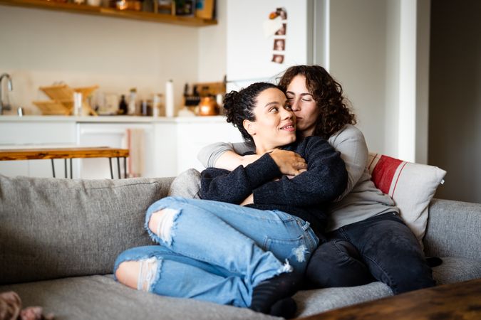 Happy female couple holding each other in living room