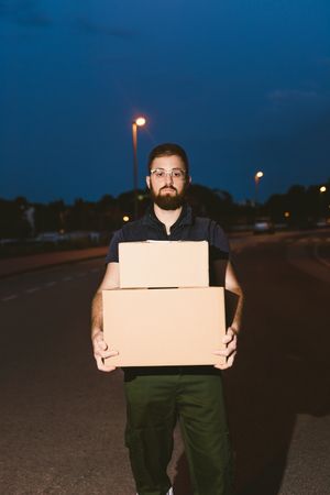 Courier delivering cardboard boxes in evening