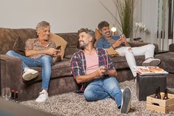 Cheerful friends using mobile phones at home