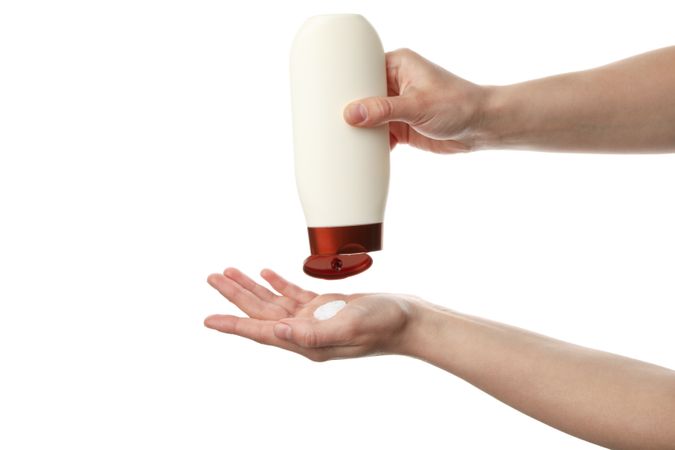 Female hands squeezing shampoo from bottle