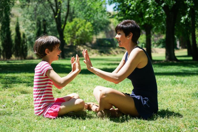 Mother and daughter clapping their hands together in park