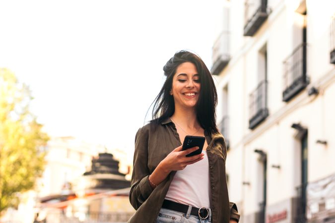 stylish young woman walking and using her mobile