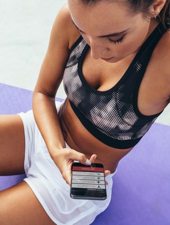 Female athlete using fitness app o her phone for exercising