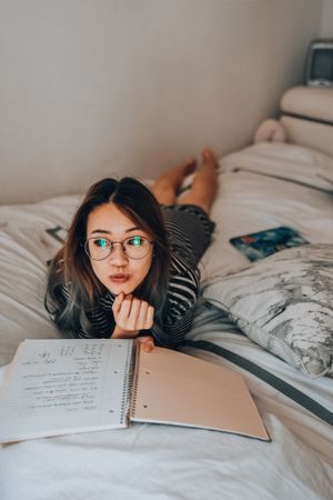 Girl doing her homework in bed