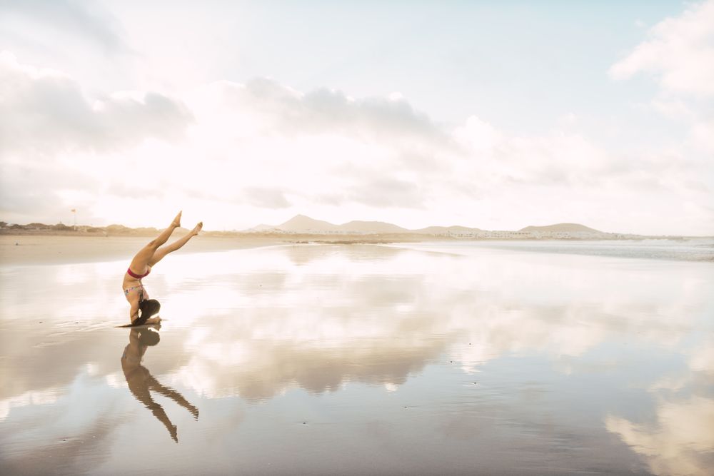 Woman doing handstand near sea