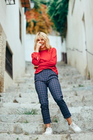 Laughing blonde woman with red shirt standing on steps outdoors