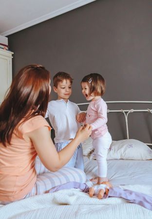 Portrait of happy mother, daughter and son playing in bed on a relaxed morning