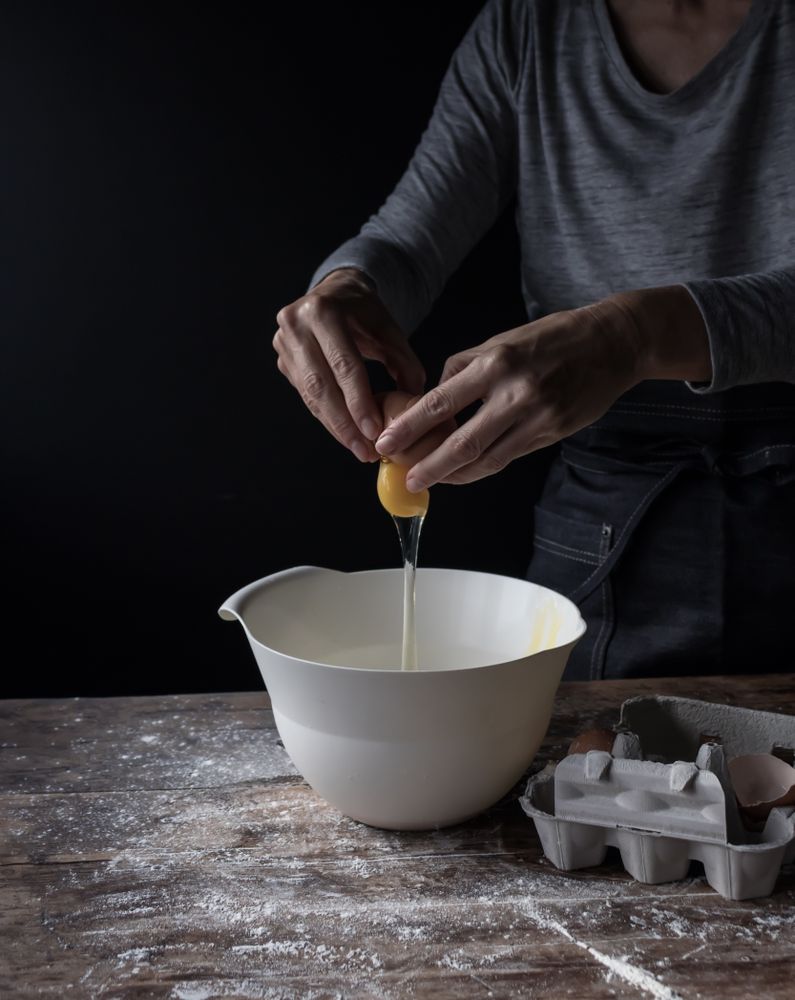 Person cracking egg in bowl on table