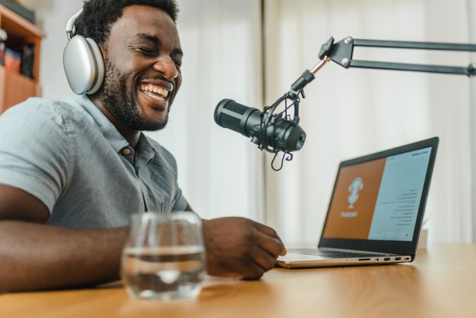Black man in headphones recording podcast and laughing