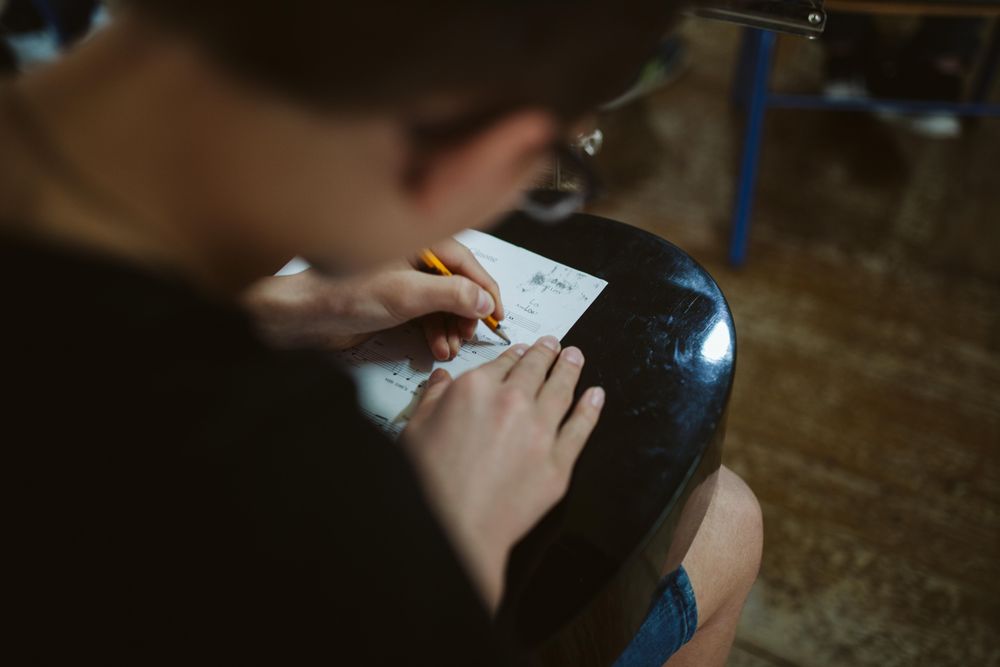 Young student writing notes on sheet music