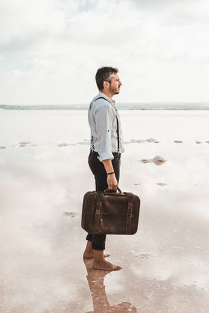 Fancy man with suitcase gazing at seaside