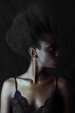 Portrait of Black woman wearing eyeliner against dark background