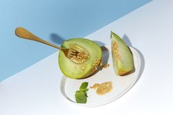 Sliced small melon on plate with spoon and fork