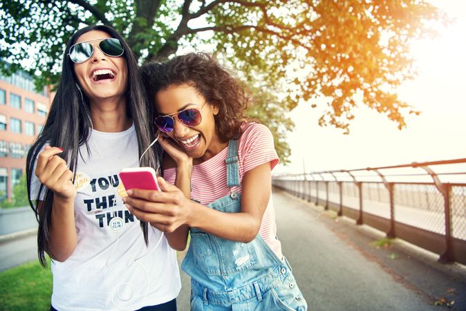 Cheerful young female adults laughing together at a park outdoors