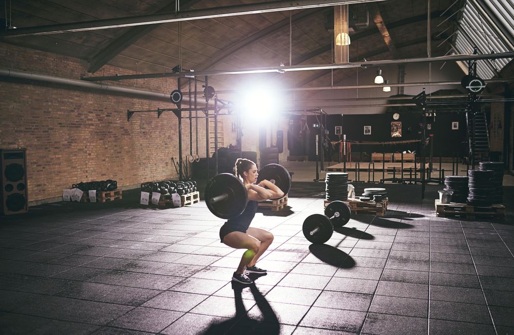 Strong woman performing a squat with weights on bar