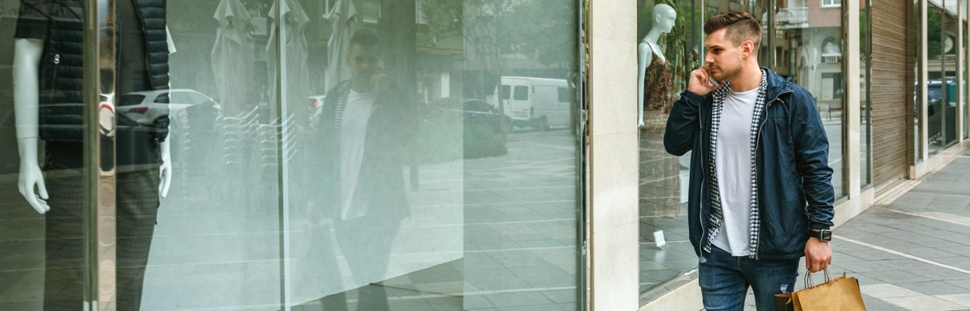 Man with shopping bags in front clothing store