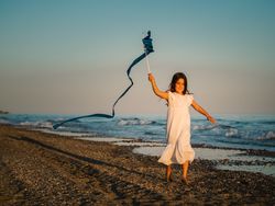 Adorable girl playing with ribbon on seaside