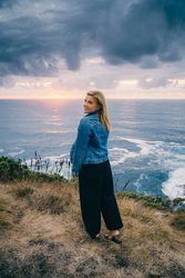Woman on seashore against dusky clouds
