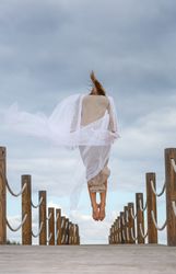 Woman with textile posing in air on footbridge