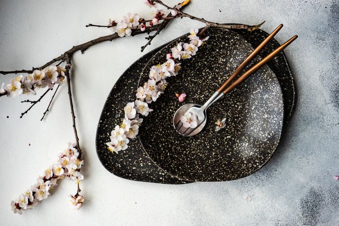 Table setting with delicate apricot blossom around elegant dark tableware