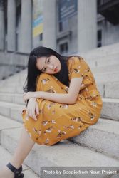 Girl in orange dress sitting on concrete stairs 0WZRWb