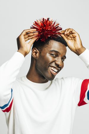 Excited Black man holding a red pompom up to his head