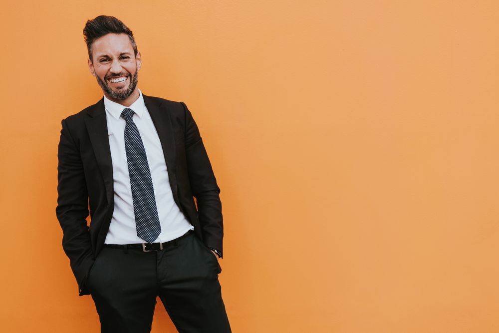 Adult stylish man in costume near orange wall