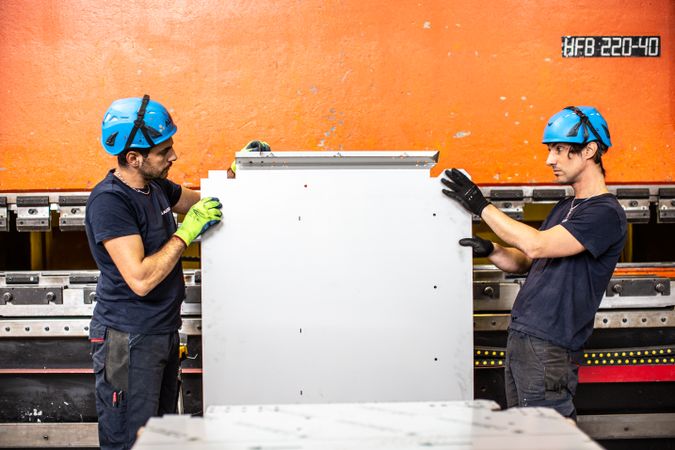 Two men with bump caps holding a metal plate