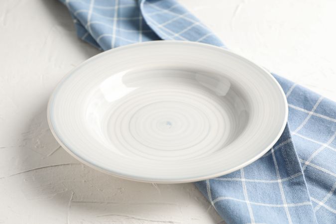 Kitchen towel with plate on blank background, closeup