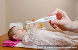 Hands holding thermometer before cute baby 5lL8Y5