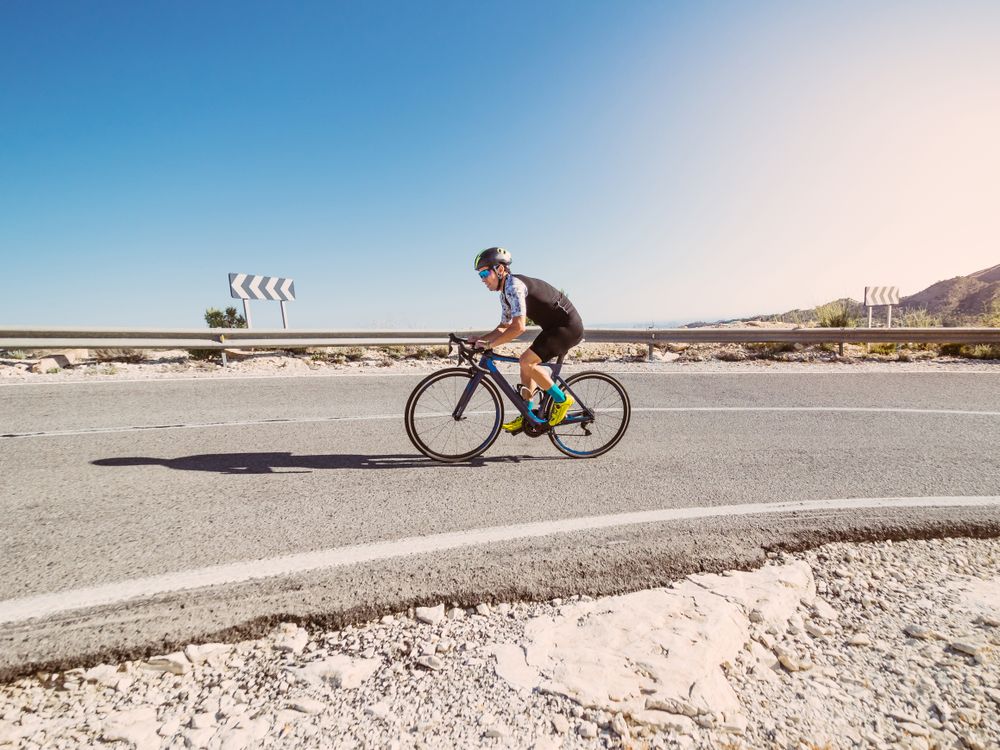 healthy man riding a bicycle on a mountain road in a sunny day