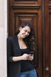 Young female using mobile phone on wooden door