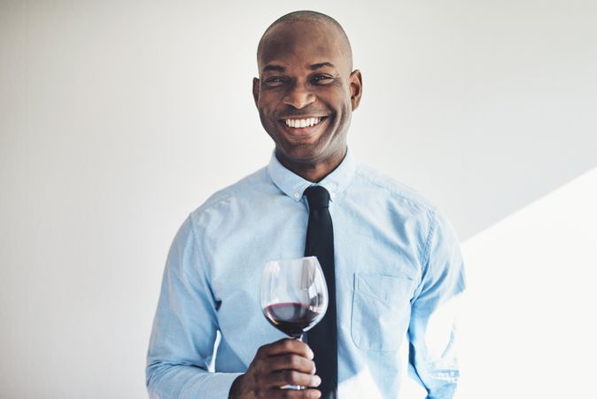 Man in shirt and tie smiling an holding a glass of red wine