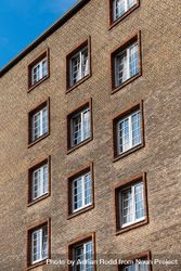Close up of windows on minimal brown brick building under blue sky 4jo6rb