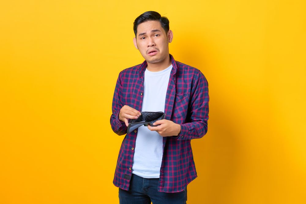 Upset man opening his empty wallet