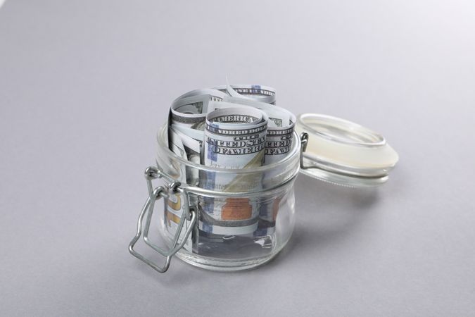 Jar with Dollar bills on gray background