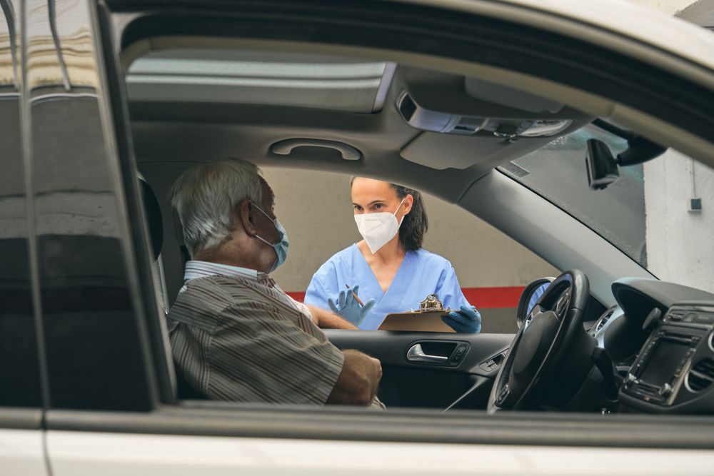 Crop physician talking to mature driver in car during drive thru