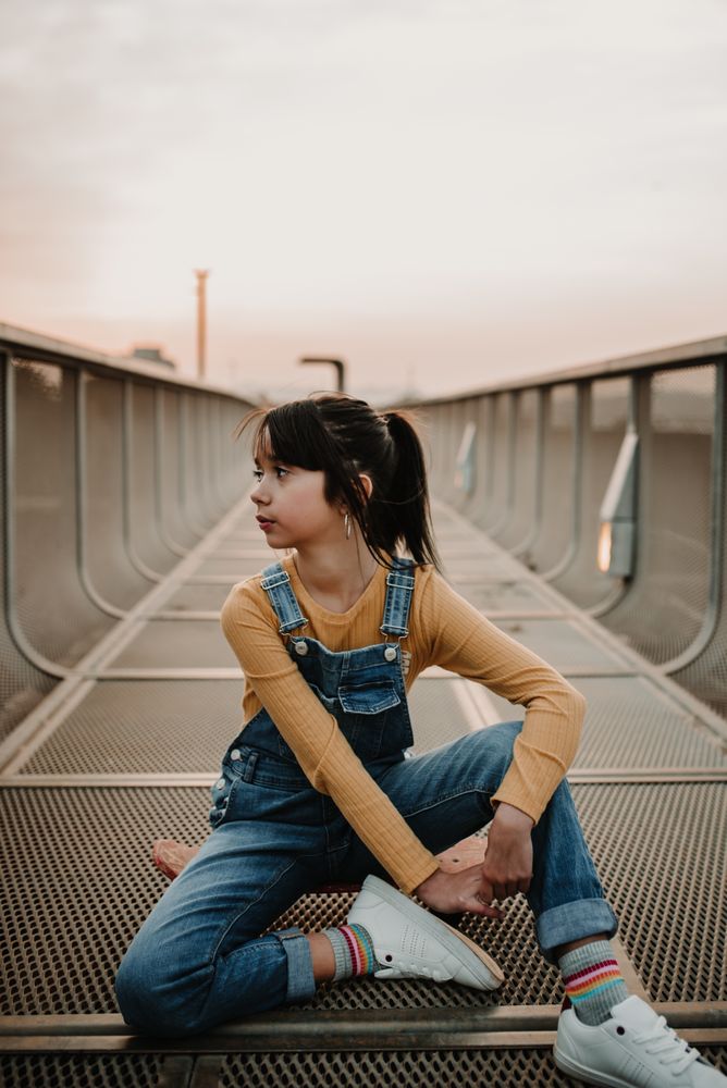 Girl sitting on skateboard on walkway