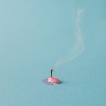 Burnt out pink candle on blue background