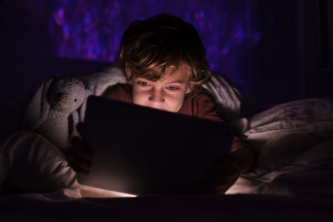 Child watching video on tablet in darkness