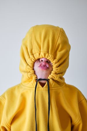 Unrecognizable child making grimace in yellow hoodie