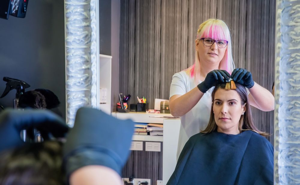 Hairdresser trying different color swathes on client in salon