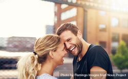 Couple laughing and hugging each other outdoors in a city bDney5