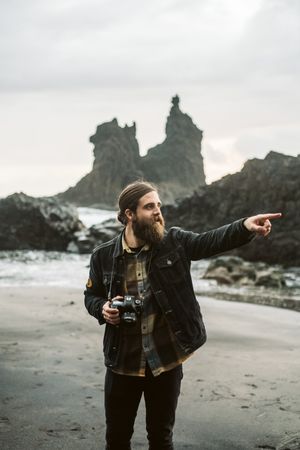 Bearded photographer standing near sea