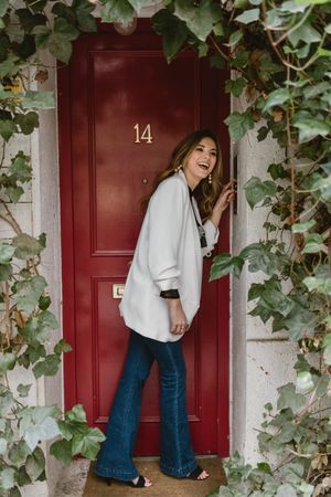 Stylish woman standing near red door