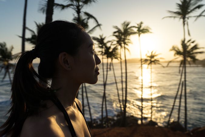 Tranquil female traveler among palms at seashore