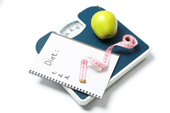 Scales, measuring tape, apple and copybook isolated on blank background