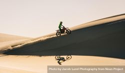 Side view of motocross rider going up over sand dunes 4ZpD30